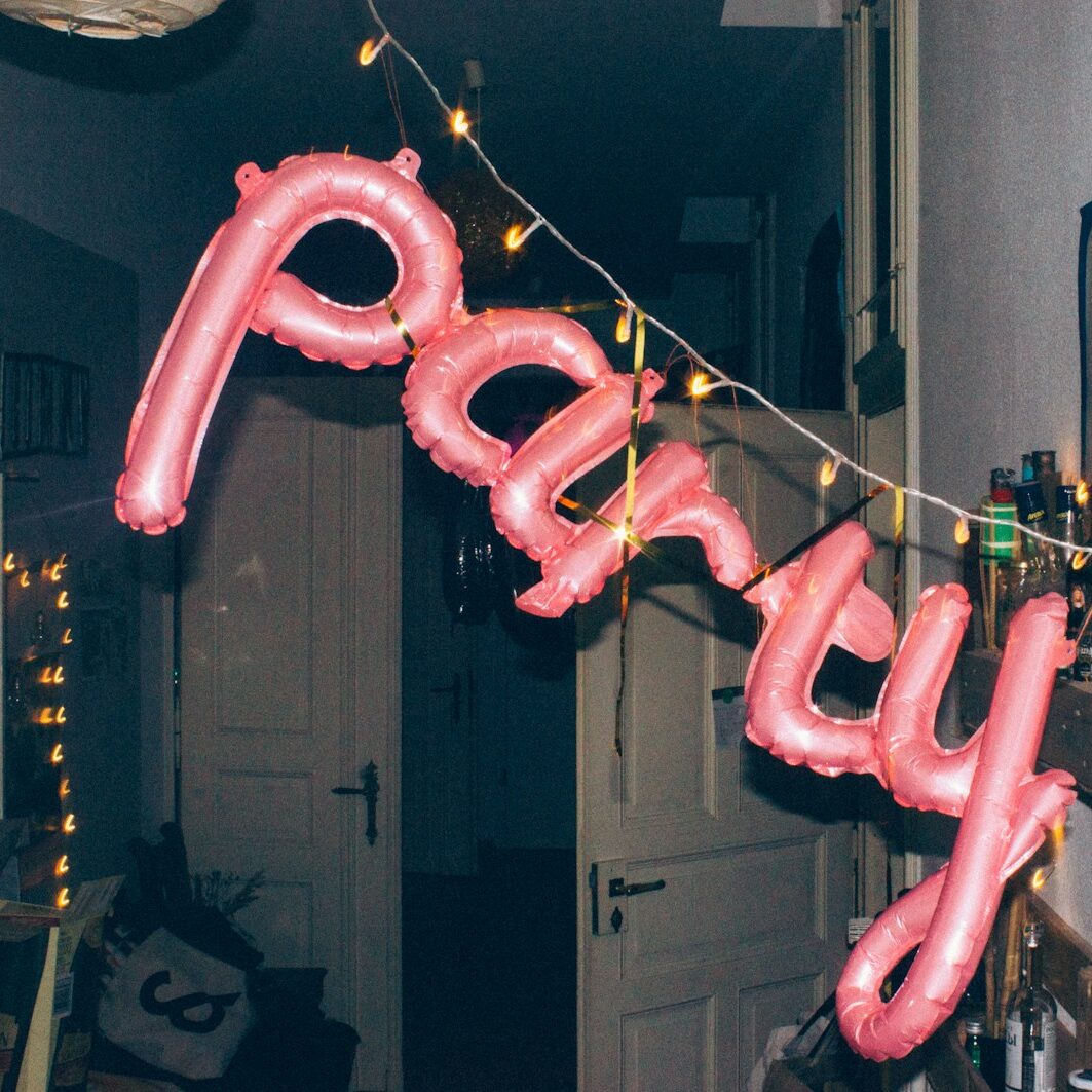 a pink balloon that says party hanging from a string